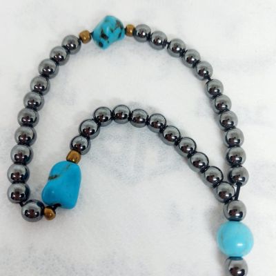 A prayer necklace made from hematite stones, with turquoise spacers.