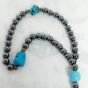 A prayer necklace made from hematite stones, with turquoise spacers.
